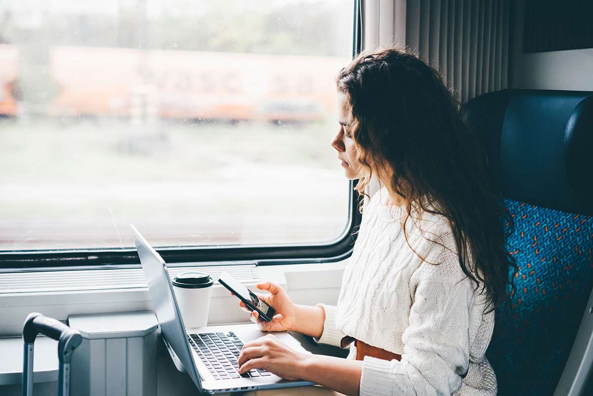 Beraterin im Zug mit Handy und Laptop