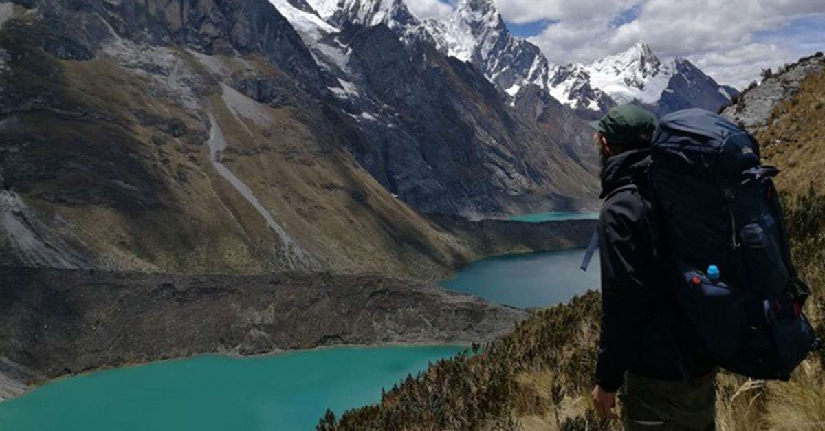 Backpacker schaut von einem Berg auf einen See in Peru